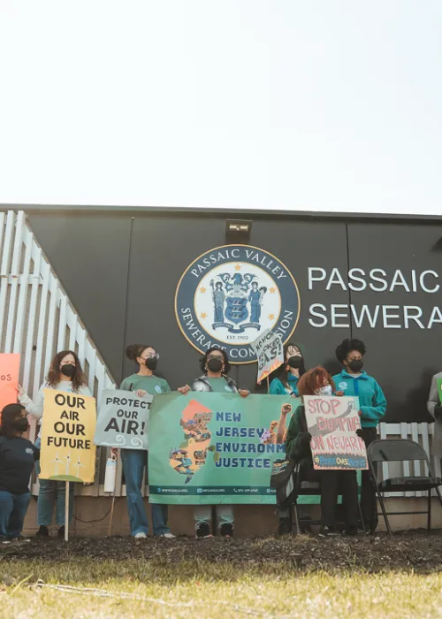 several people in a line holding signs for clean water