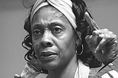 black and white photo of woman with microphone, white headband