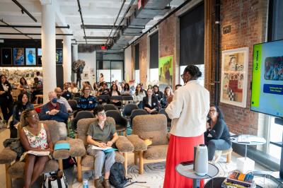 rows of audience seated in bright room, watching presenter speak