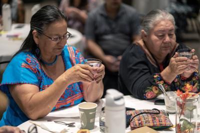two women in prayer with cups of water