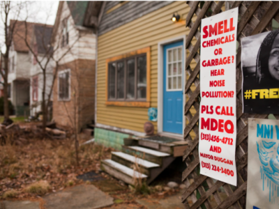 home with a blue door, sign about pollution on pole 
