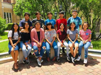 group of young people seated and standing on a courtyard bench