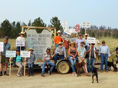 group of people on farmland trailer, holding up signs
