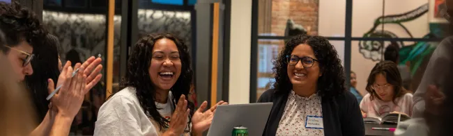 three people in foreground clapping and laughing