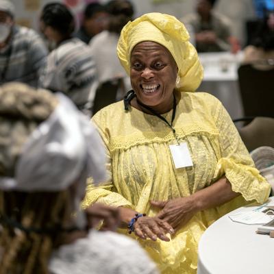 Woman in yellow dress and headscarf smiling at conference